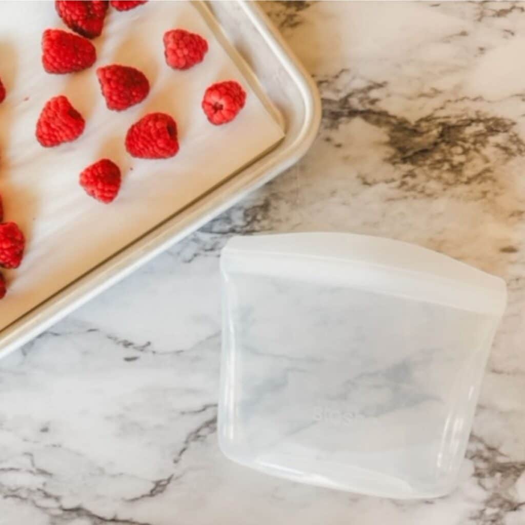 raspberries being added to a freezer safe container