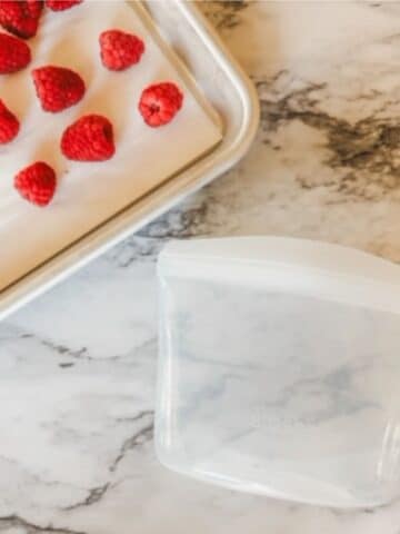 raspberries being added to a freezer safe container