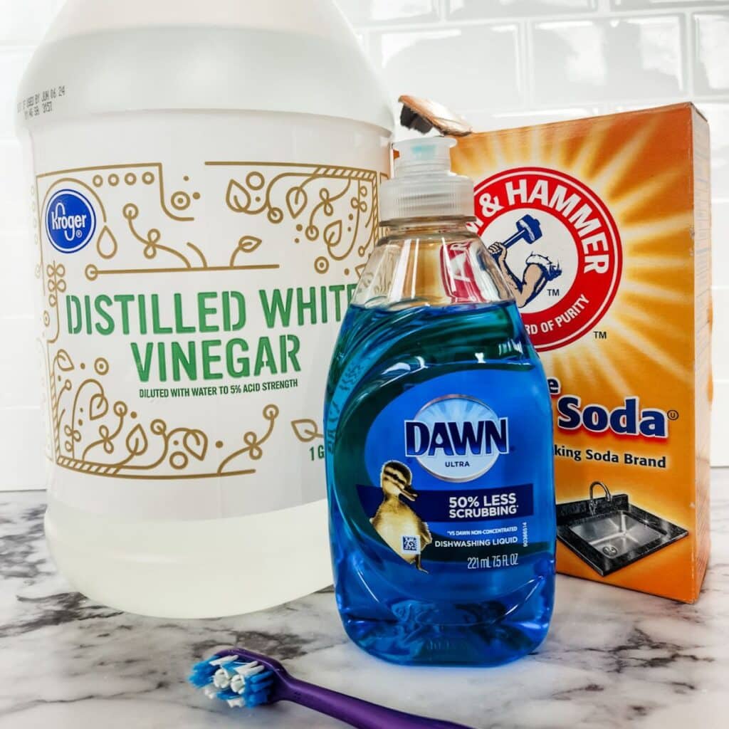 vinegar, dish soap, and baking soda sitting next to a toothbrush.