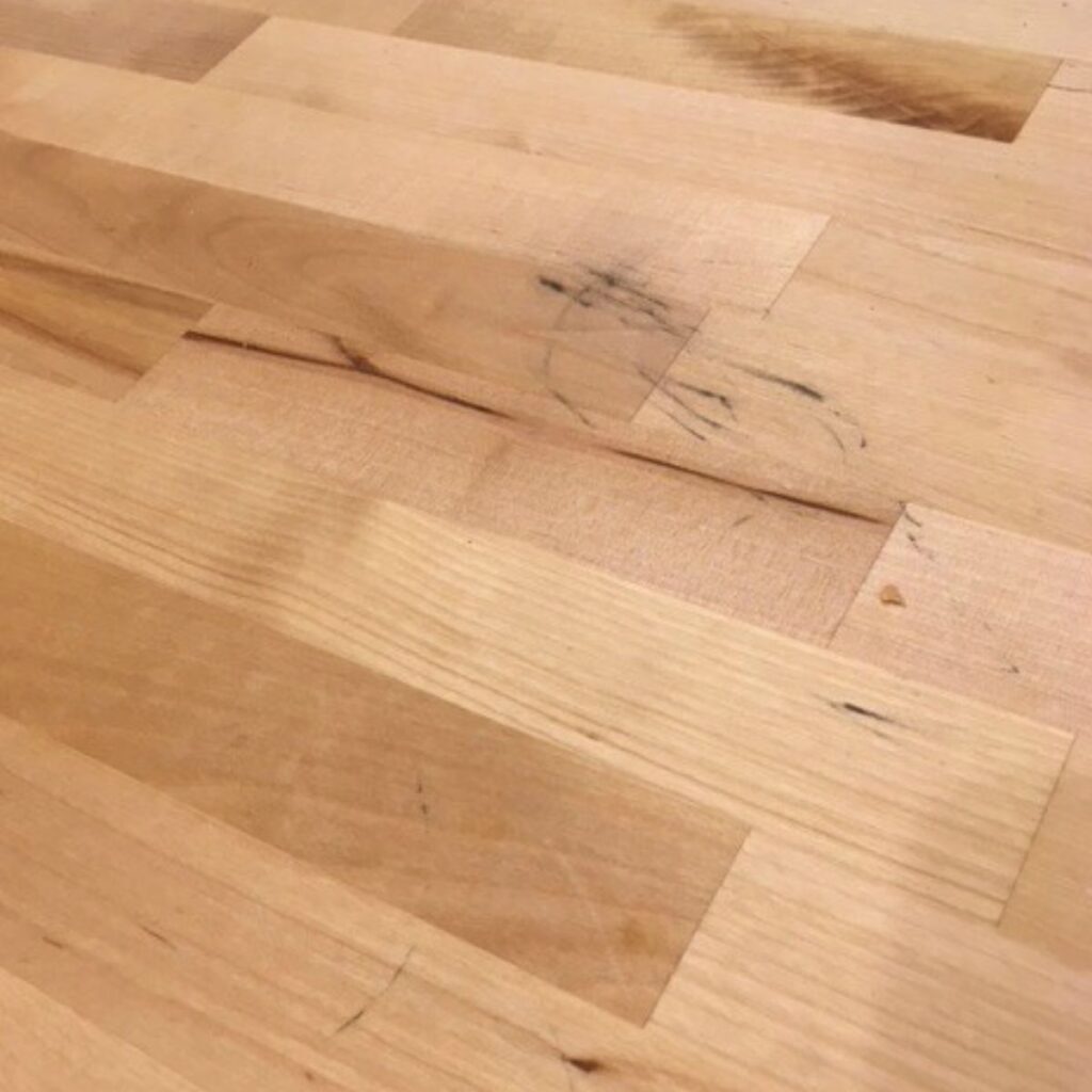 A dirty butcher block countertop with black stains.