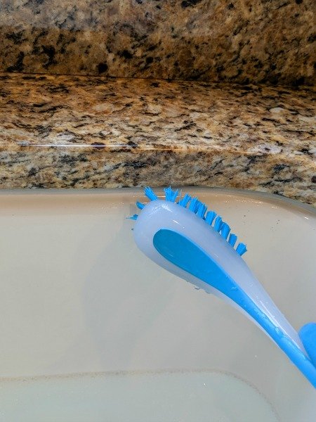 using a brush a clean a kitchen sink