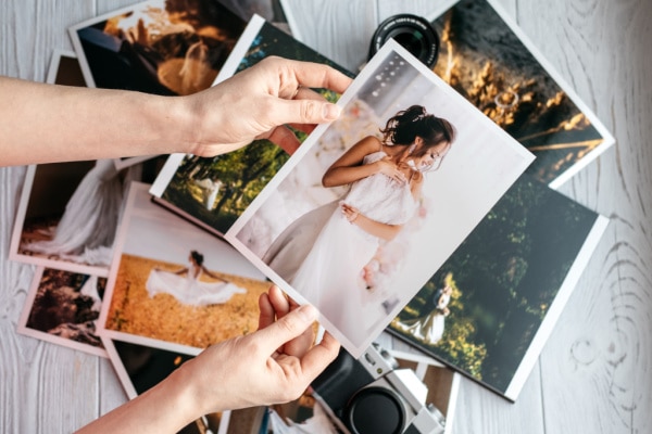 a stack of printed pictures, and holding a wedding photo.