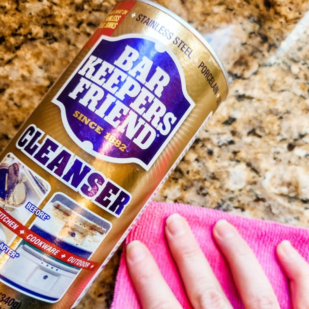 Using a pink towel to clean a granite counter with bar keepers friend.