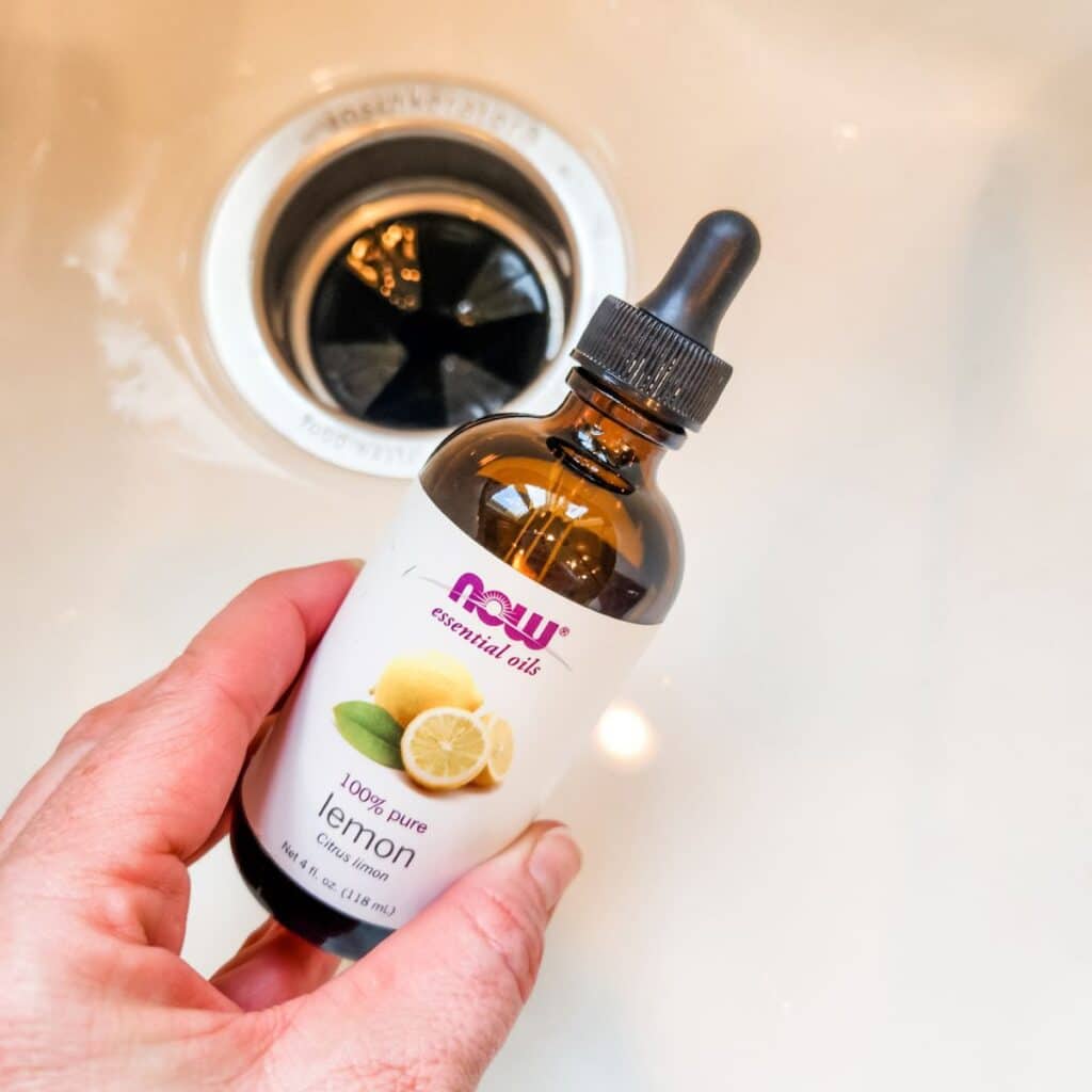 holding a bottle of lemon essential oil over the sink to make the disposal smell better.