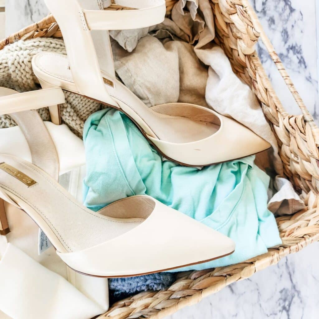 High heel shoes in top of a basket with clothes that needs decluttering.