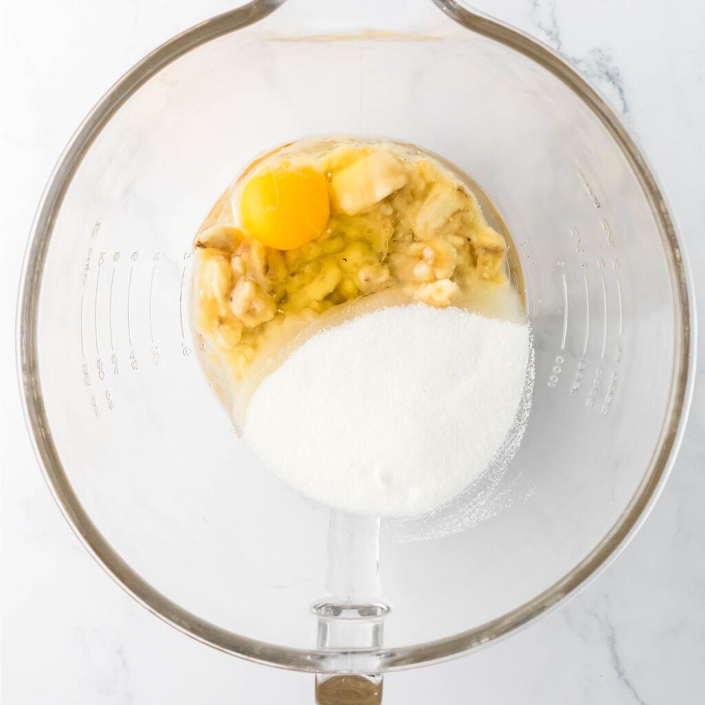 A bowl with mashed bananas, egg, and sugar.